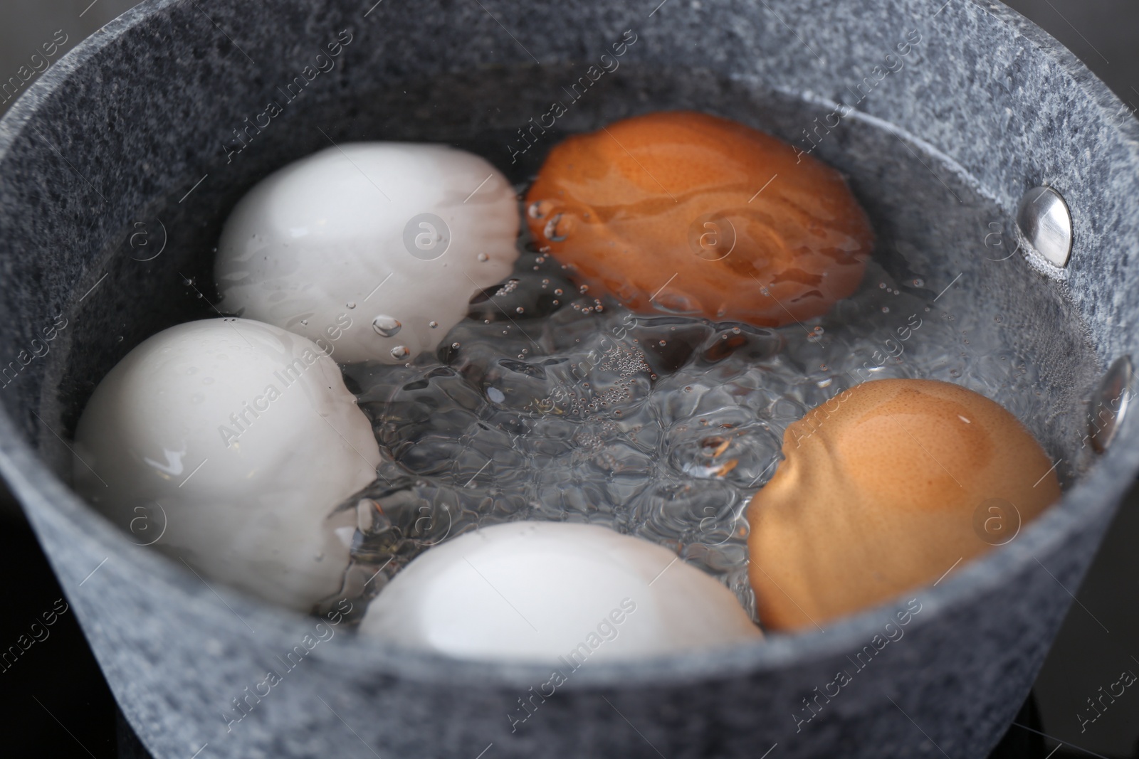 Photo of Chicken eggs boiling in saucepan, closeup view