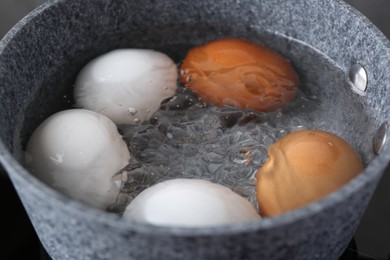 Chicken eggs boiling in saucepan, closeup view