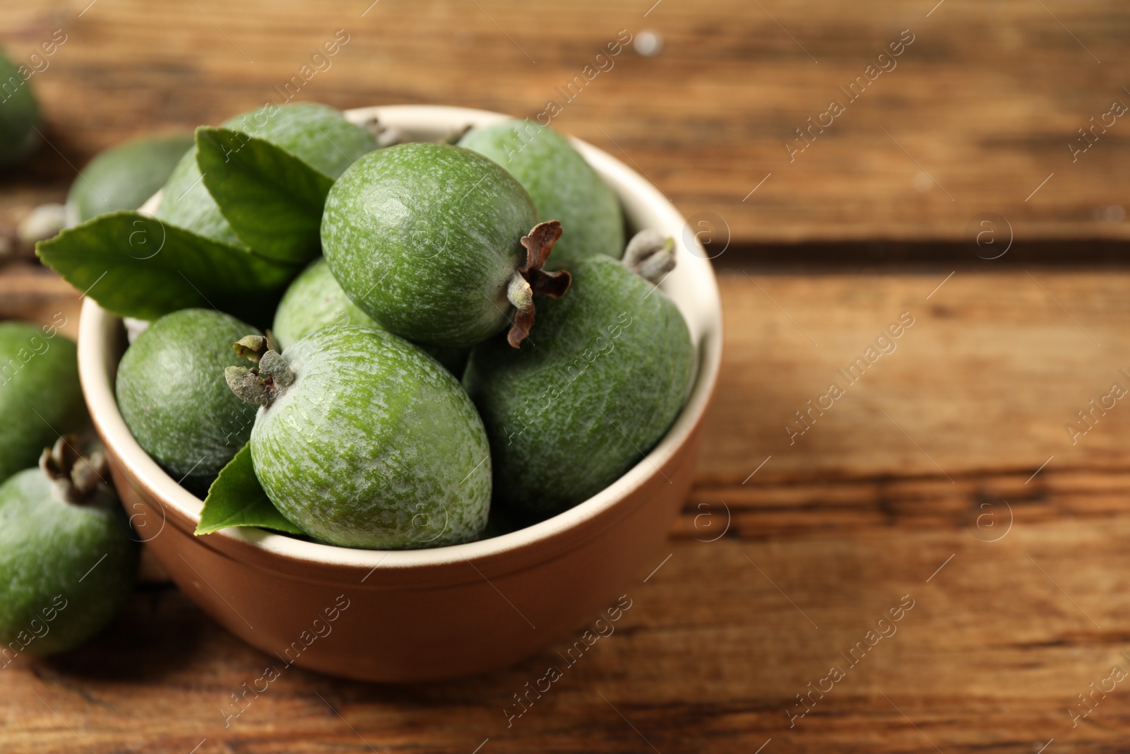 Photo of Fresh green feijoa fruits on wooden table, closeup. Space for text