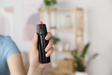 Photo of Woman using pepper spray indoors, closeup view