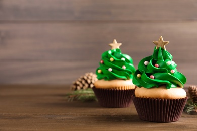 Photo of Christmas tree shaped cupcakes on wooden table. Space for text