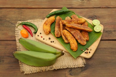 Photo of Delicious fried bananas, fresh fruits and different peppers on wooden table