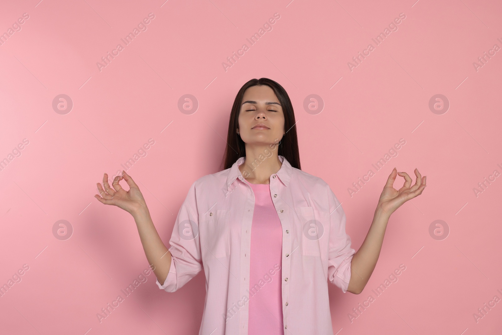 Photo of Young woman meditating on pink background. Zen concept