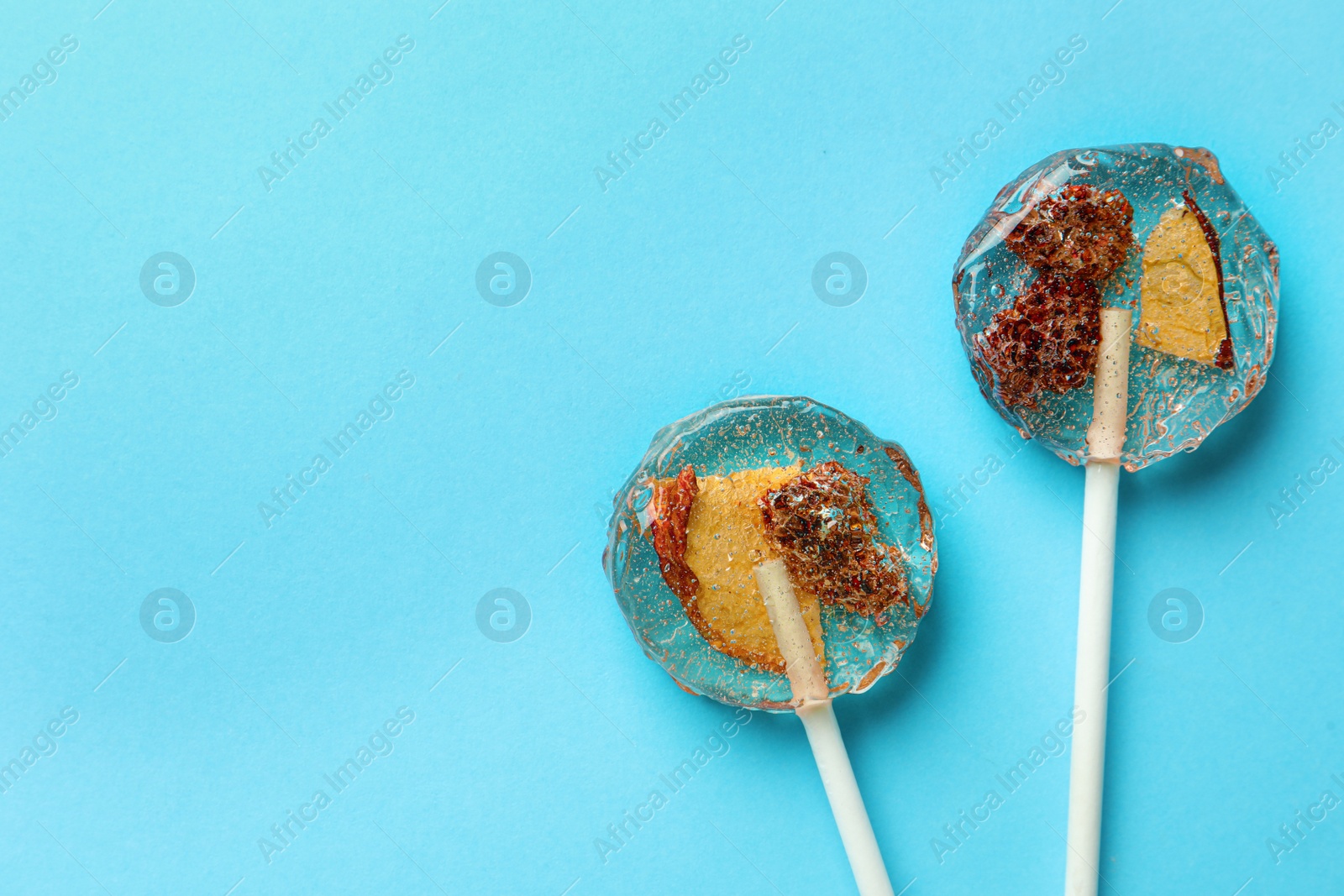 Photo of Sweet colorful lollipops with berries on light blue background, flat lay. Space for text