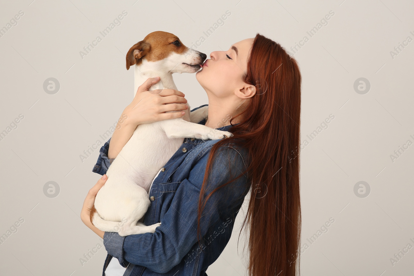 Photo of Woman kissing cute Jack Russell Terrier dog on white background