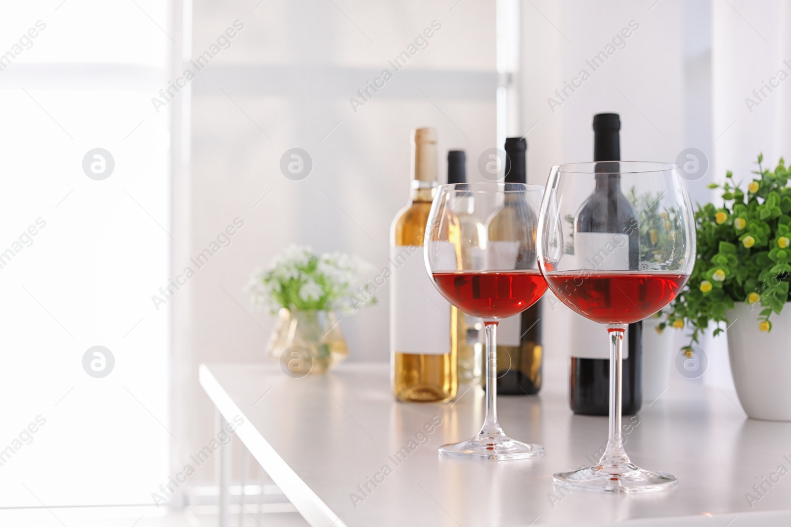 Photo of Glasses and bottles with delicious wine on table indoors