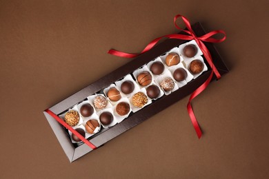 Box with delicious chocolate candies on brown table, top view