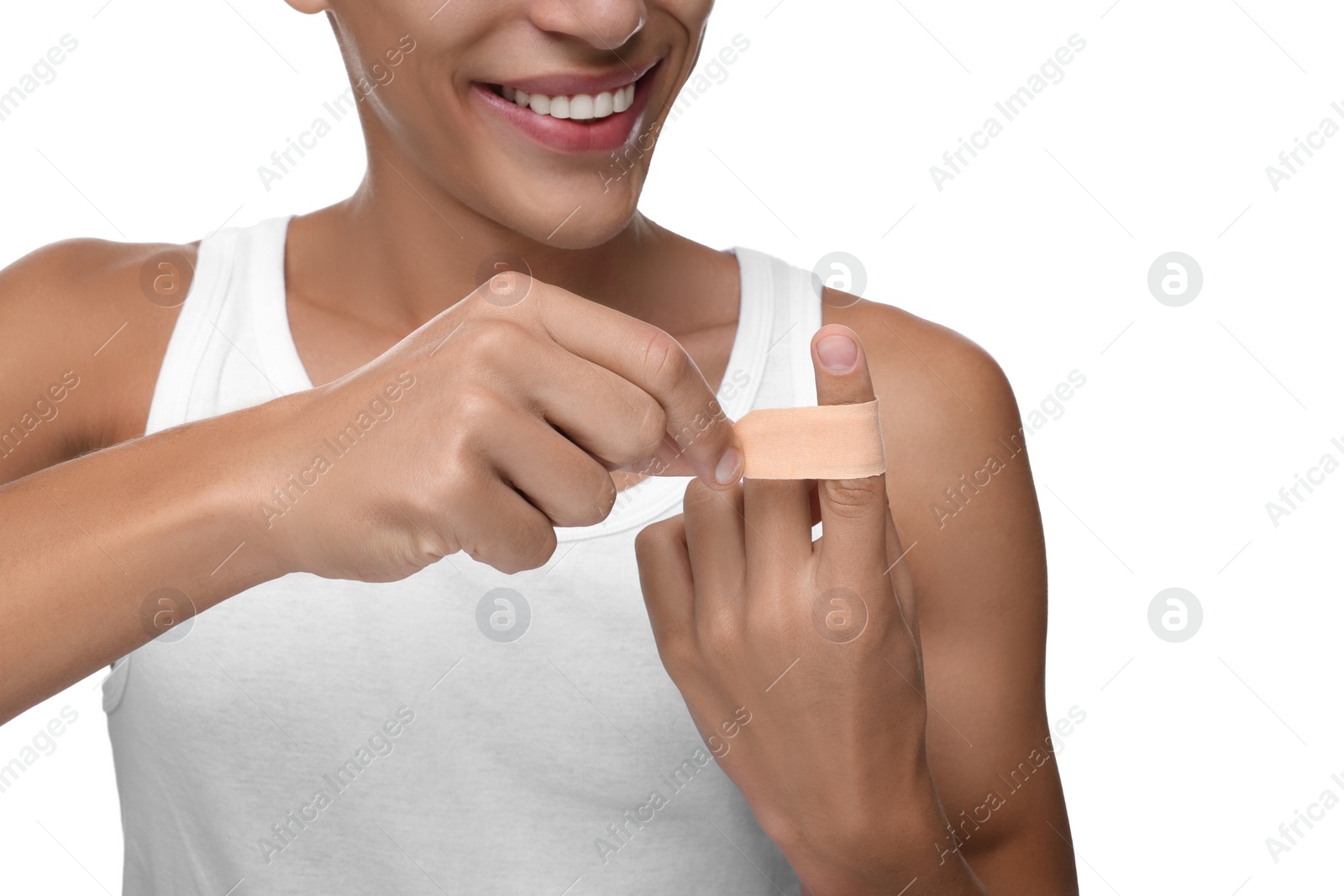 Photo of Man putting sticking plaster onto finger on white background, closeup