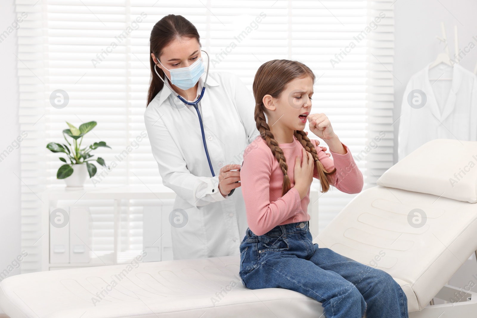 Photo of Doctor examining coughing girl in hospital. Cold symptoms