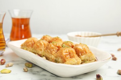 Delicious baklava with pistachios and scattered nuts on white marble table