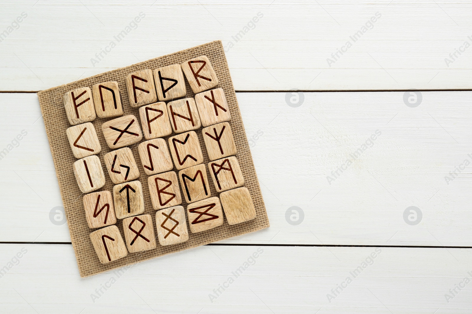 Photo of Runes with different symbols on white wooden table, top view. Space for text