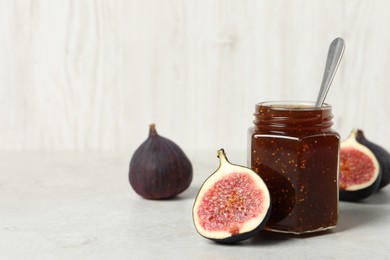 Photo of Glass jar with tasty sweet jam and fresh figs on white table, space for text