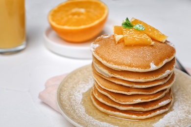 Tasty pancakes with orange on table