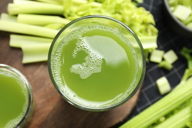 Glasses of delicious celery juice and vegetables on wooden board, flat lay