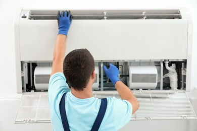 Photo of Technician installing and checking air conditioner indoors