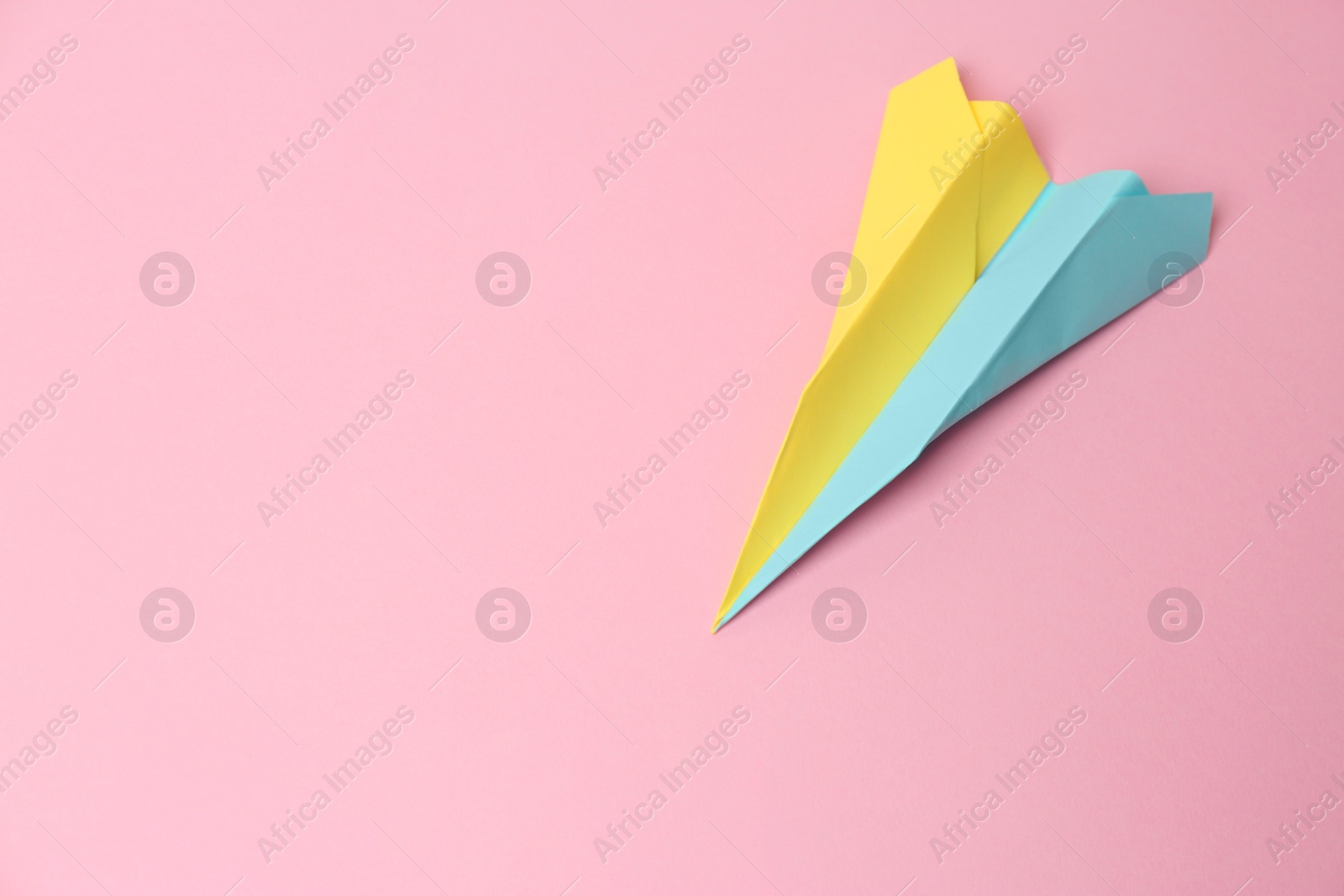 Photo of Colorful paper plane on pink background, top view. Space for text