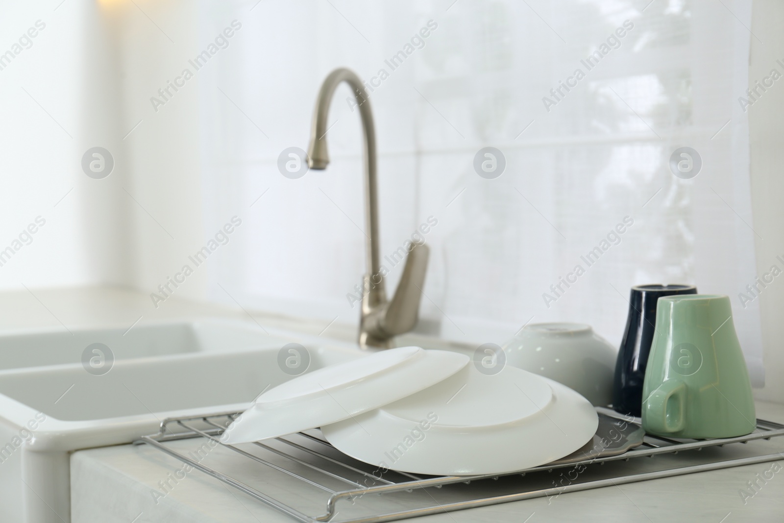 Photo of Clean dishes drying on rack in modern kitchen