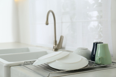 Photo of Clean dishes drying on rack in modern kitchen