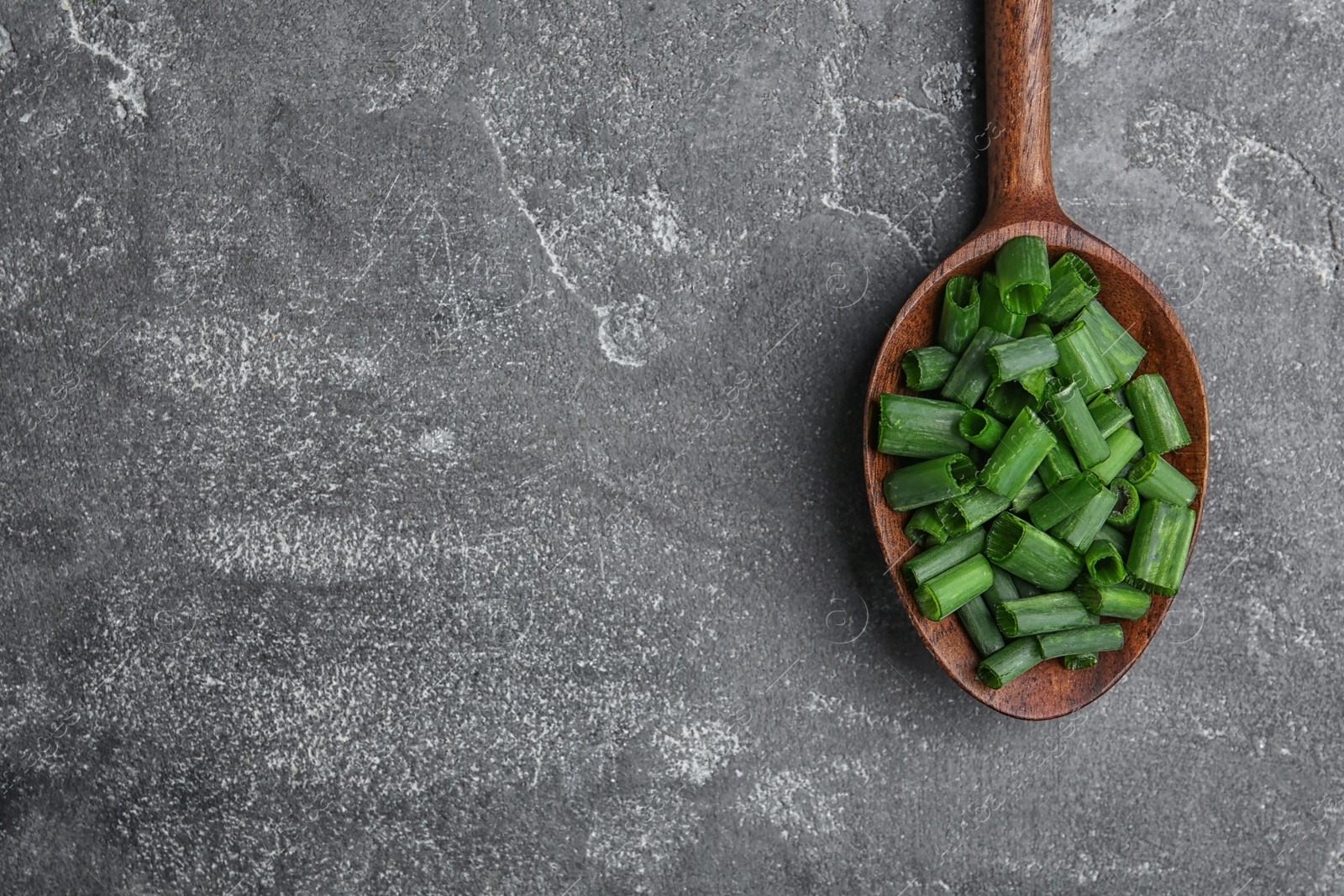 Photo of Spoon with chopped green onion on table, top view