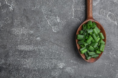 Spoon with chopped green onion on table, top view