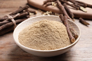 Photo of Dried sticks of liquorice root and powder on wooden table, closeup