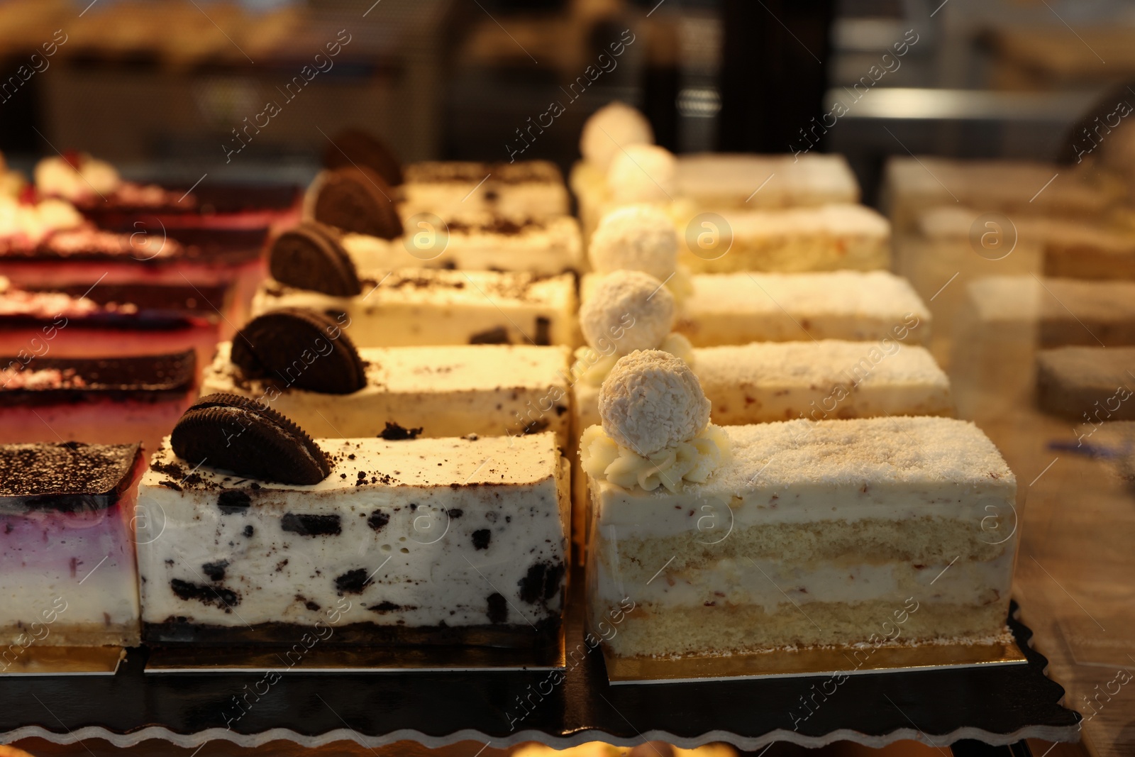 Photo of Different delicious cakes on counter in bakery shop, closeup