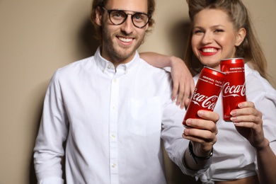 Photo of MYKOLAIV, UKRAINE - NOVEMBER 28, 2018: Young couple with Coca-Cola cans on color background