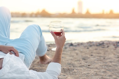 Young man with glass of wine on beach