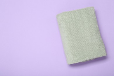 Photo of Soft towel on violet background, top view. Space for text