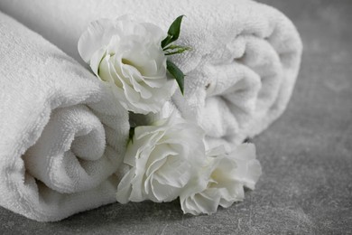 White soft towels with flowers on grey table, closeup