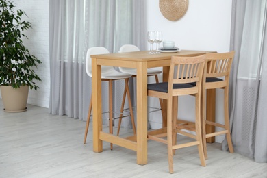 Stylish room interior with dining table and bar stools near white wall