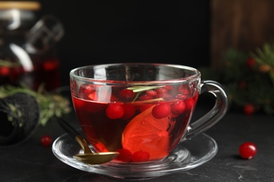 Photo of Tasty hot cranberry tea with rosemary and lemon on black table