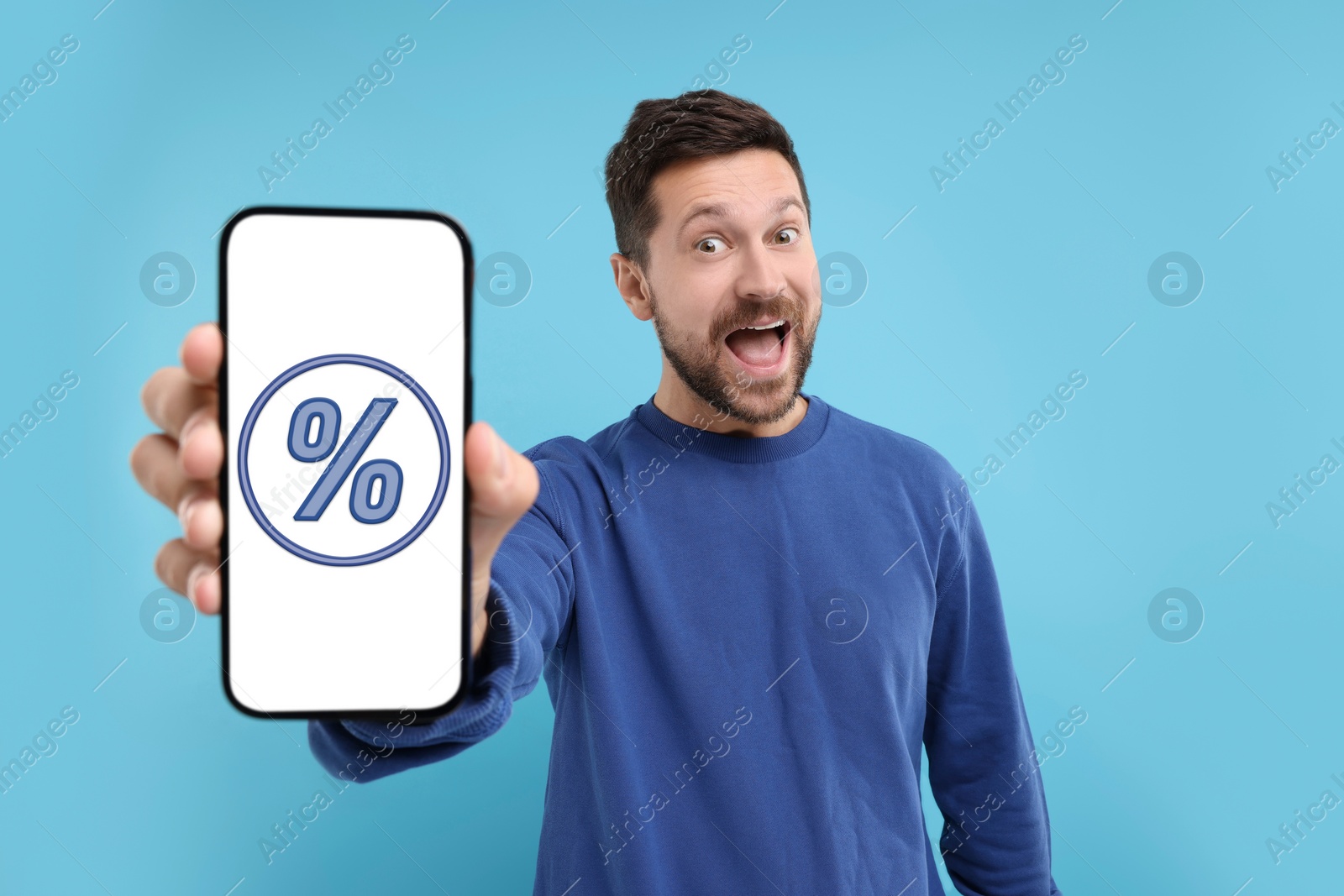 Image of Discount, offer, sale. Emotional man showing mobile phone with percent sign on screen, background