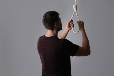 Man with rope noose on light grey background, back view