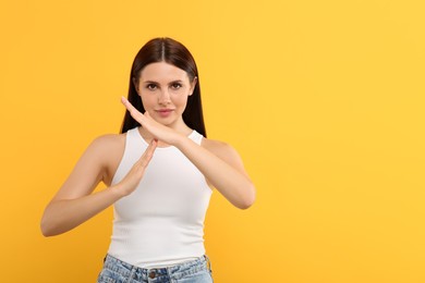 Photo of Woman showing time out gesture on orange background, space for text