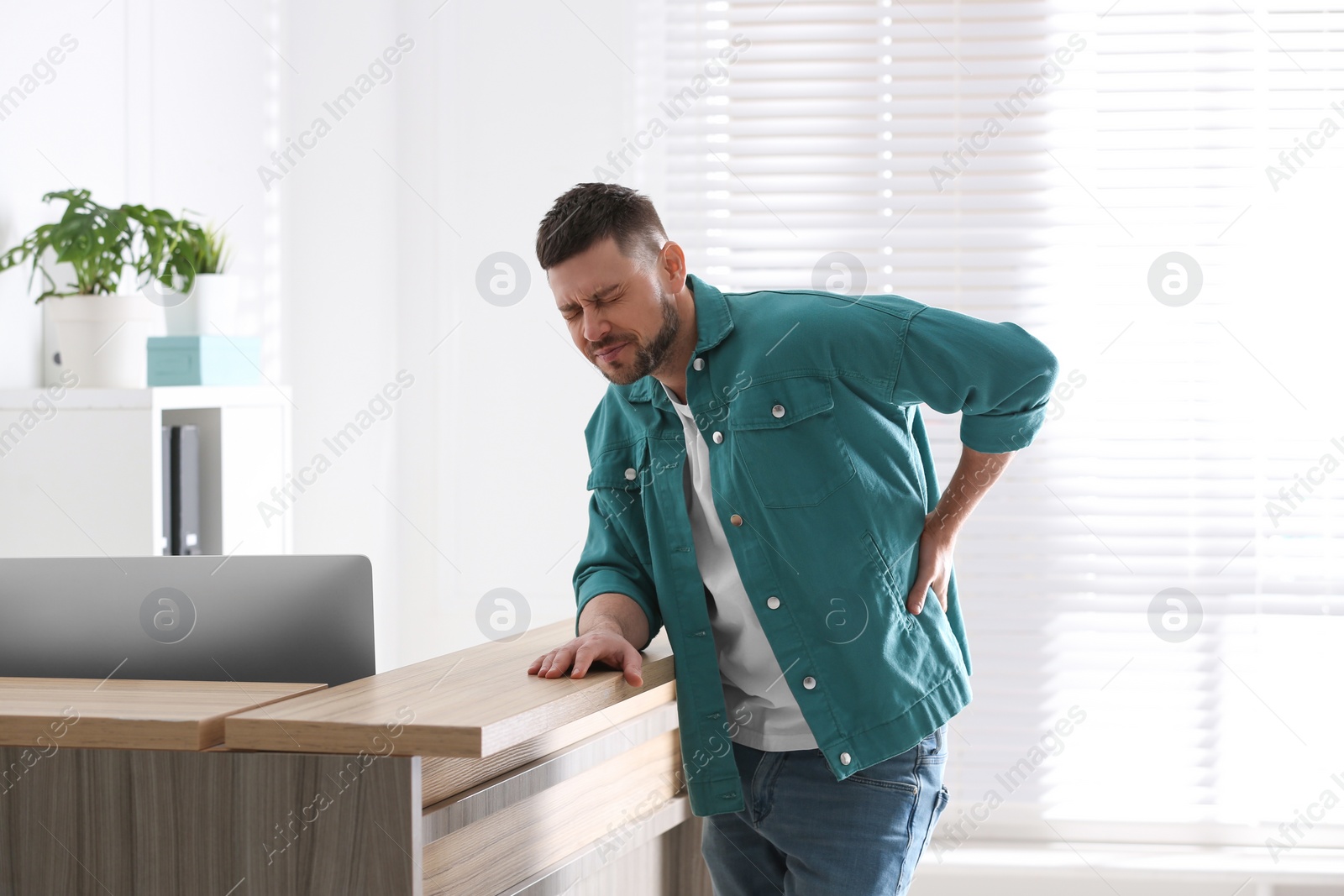 Photo of Man suffering from back pain in office. Bad posture problem