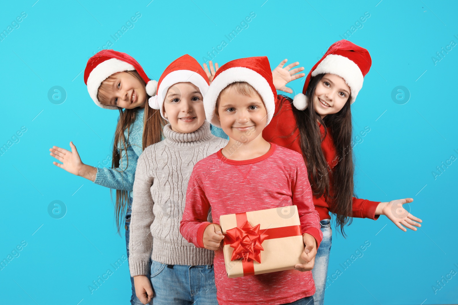 Photo of Cute little children in Santa hats on color background. Christmas celebration