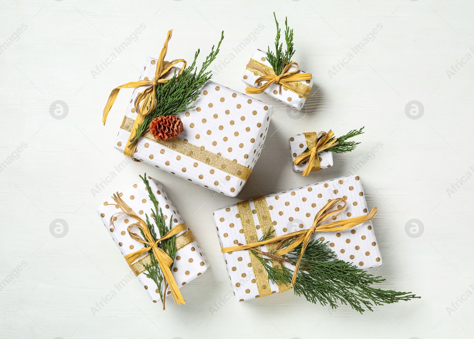 Photo of Christmas gift boxes with fir branches on white wooden background, flat lay