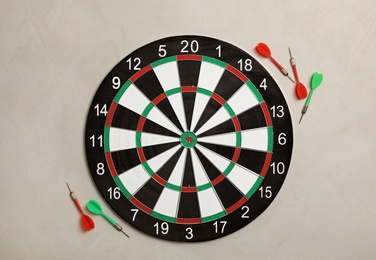 Photo of Dart board with color arrows on light stone background, top view