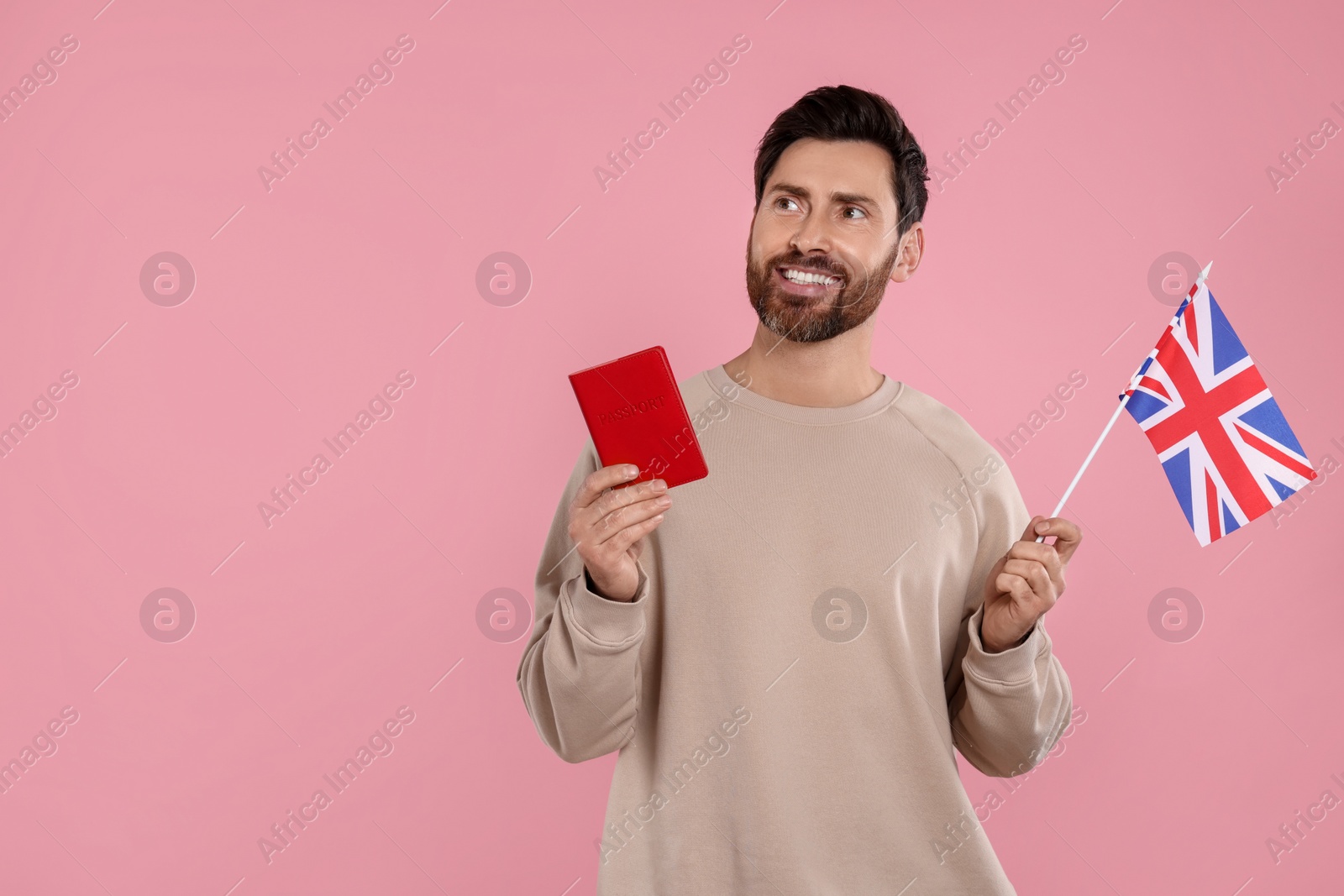 Photo of Immigration. Happy man with passport and flag of United Kingdom on pink background, space for text