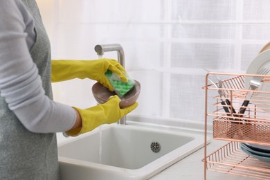 Photo of Woman washing plate above sink in modern kitchen, closeup