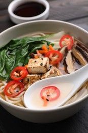 Photo of Bowl of vegetarian ramen and spoon on table, closeup