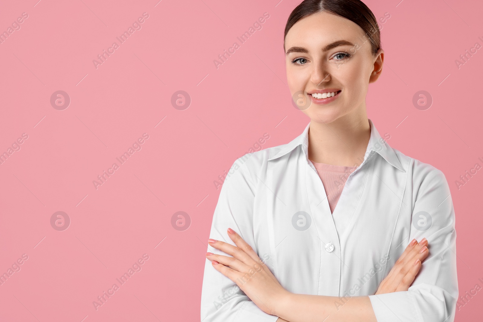 Photo of Cosmetologist in medical uniform on pink background, space for text