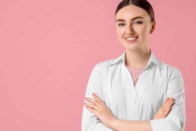 Cosmetologist in medical uniform on pink background, space for text