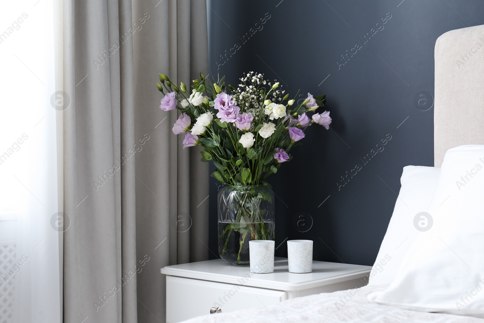 Photo of Bouquet of beautiful Eustoma flowers on nightstand in bedroom
