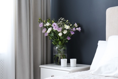 Bouquet of beautiful Eustoma flowers on nightstand in bedroom