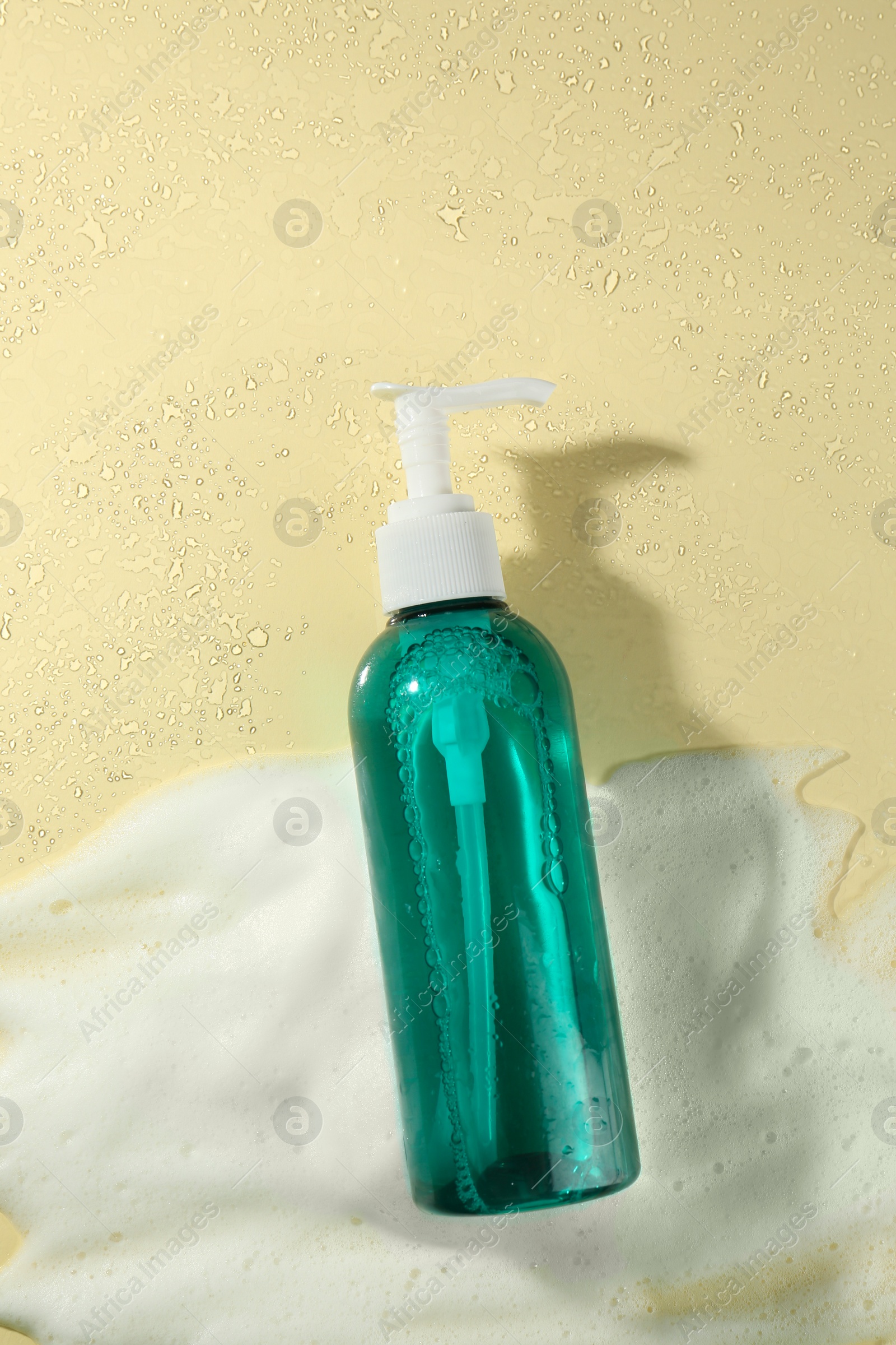 Photo of Bottle of face cleanser and white foam on beige background, top view. Skin care cosmetic