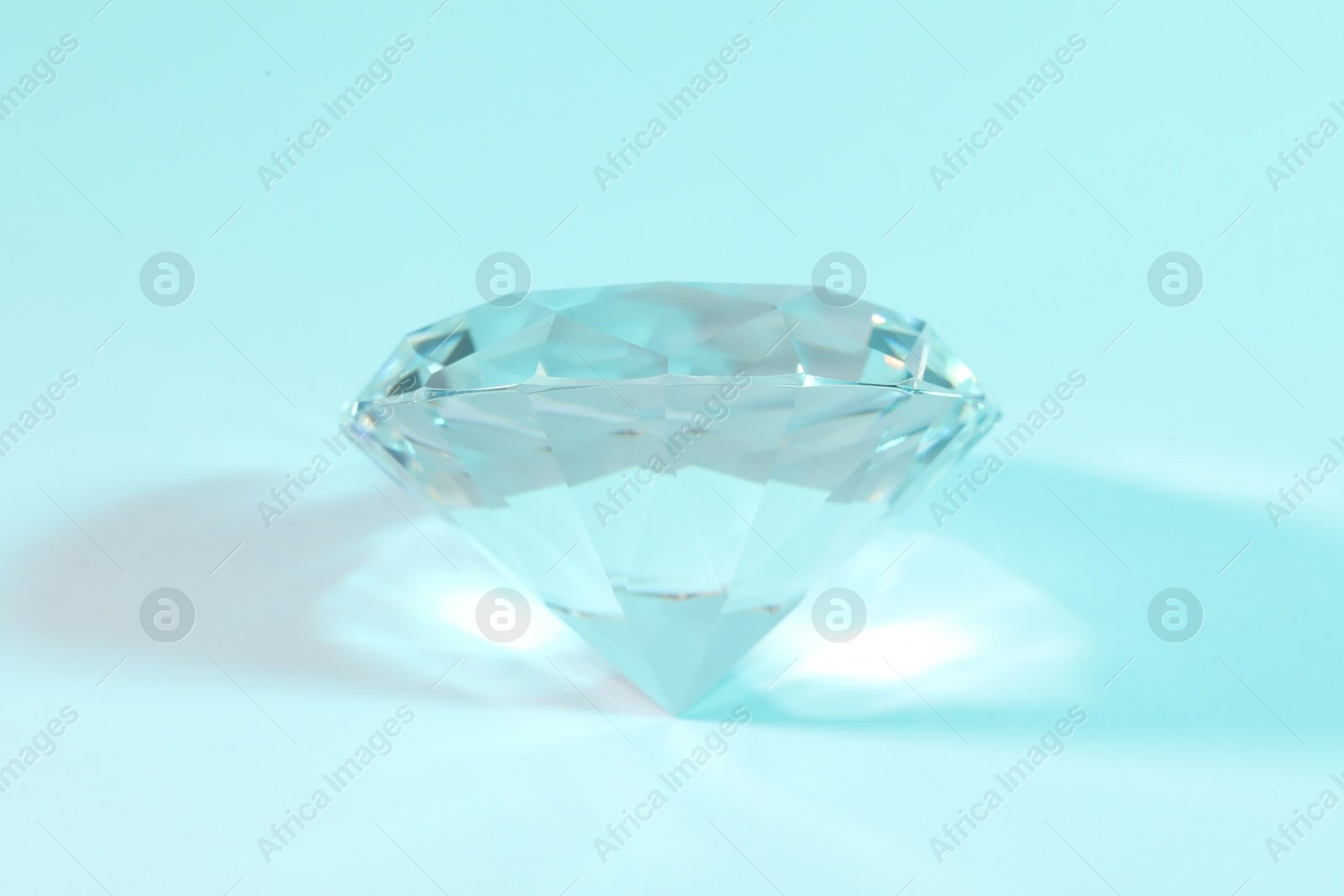 Photo of Beautiful dazzling diamond on light blue background