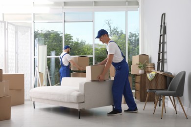 Moving service employees with cardboard boxes in room