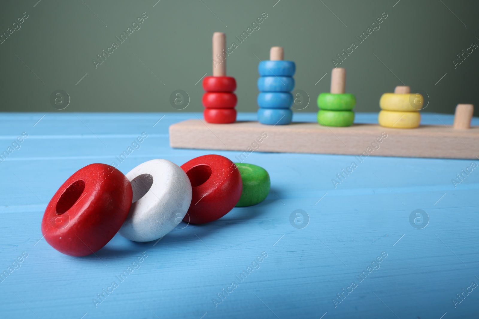 Photo of Stacking and counting game pieces on light blue wooden table, closeup with space for text. Motor skills development